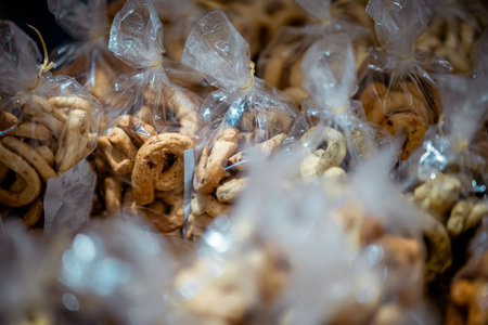 Close-up of traditional Apulian biscuits packed in clear plastic bags at a market in Bari, showing rustic shapes and textures, with warm tones and shallow depth of field highlighting local Italian food culture.の写真素材
