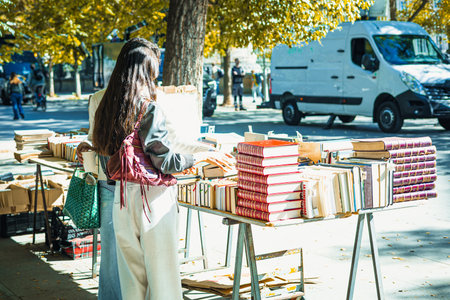 The street of Cuesta de Moyano in Madrid is shown, known for its permanent open-air book fair. Thirty bluish-grey wooden stalls sell second-hand, rare, and out-of-print books along this pedestrian hill.の写真素材