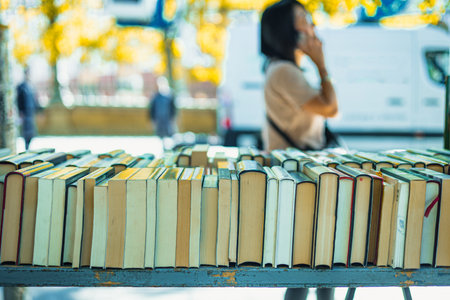 The street of Cuesta de Moyano in Madrid is shown, known for its permanent open-air book fair. Thirty bluish-grey wooden stalls sell second-hand, rare, and out-of-print books along this pedestrian hill.の写真素材