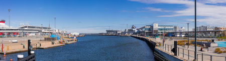 Calm blue water of a modern harbor in Tallinn. In the background, contemporary glass buildings under...