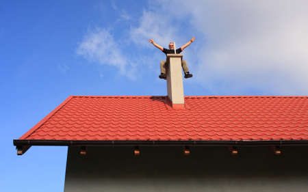Young man sitting on a chimney topの写真素材
