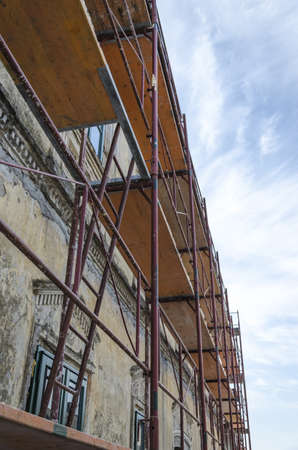 Scaffold surrounding old house during renovation works の写真素材