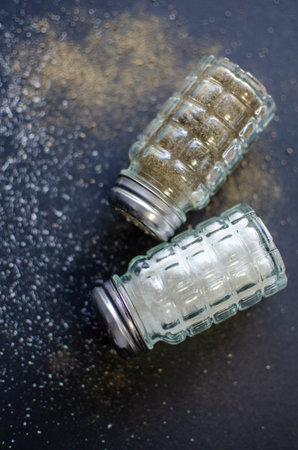 Salt and Pepper Shakers on Dark Background: Minimalist Culinary Still Lifeの写真素材