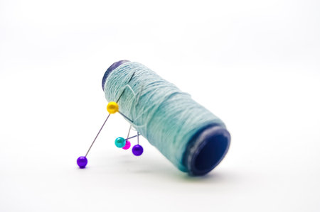 a roll of sewing thread pierced by a pin isolated on white background with copy spaceの写真素材