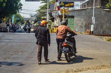 two people were guiding a motorbike because it had broken down at a railway crossing, Indonesia, 28...