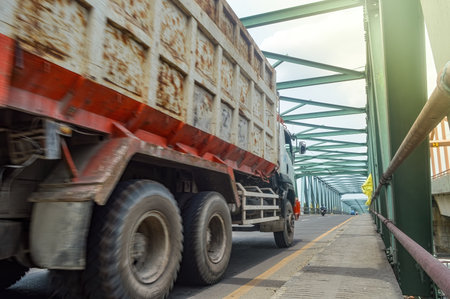 An dump truck passes a long steel truss bridgeの写真素材