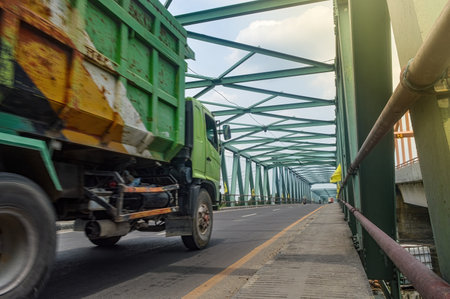 An dump truck passes a long steel truss bridgeの写真素材