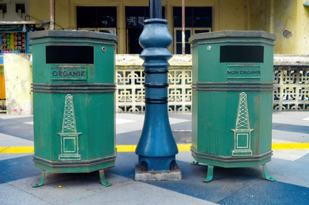 two green trash cans on the pedestrian or pathway or sidewalkの写真素材