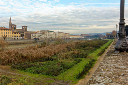Florence firenze italy italia and arno river with buildings grass and flowers on the shoreの写真素材