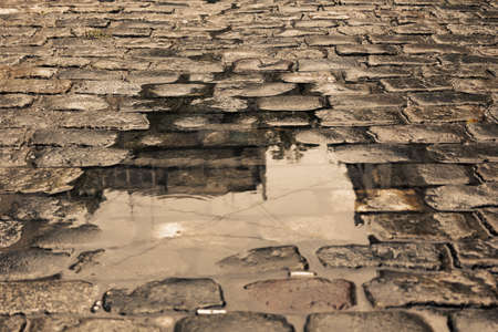 Wet cobbled street with a puddle on sunset on a rainy day in Buenos Airesの写真素材