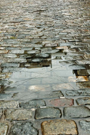 Wet cobbled street with a puddle on sunset on a rainy day in Buenos Airesの写真素材