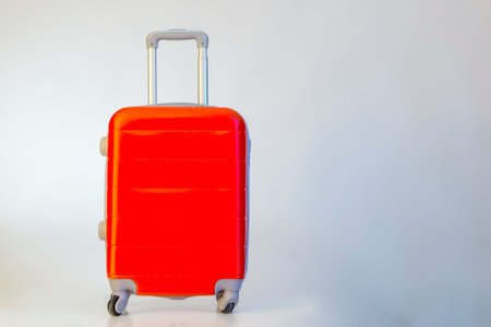 Red suitcase on white background, ready for vacation.の写真素材