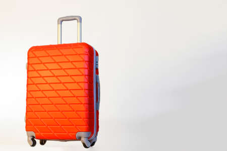 Red suitcase on white background, ready for vacation.の写真素材