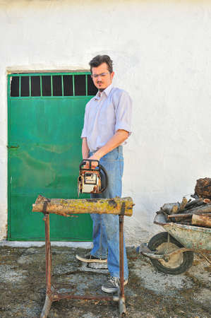 Farmer cutting firewood in a rural village, with chainsawの写真素材