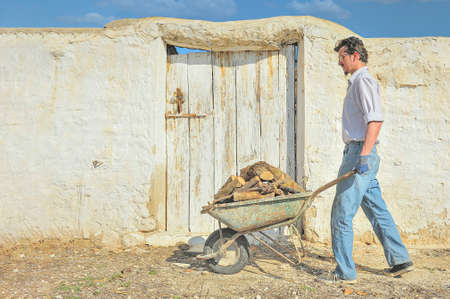 Transporting firewood in a rural village, with an old wheelbarrow.の写真素材