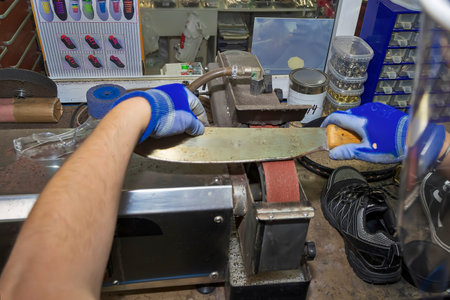 Young shoemaker mending footwear in repair shop.