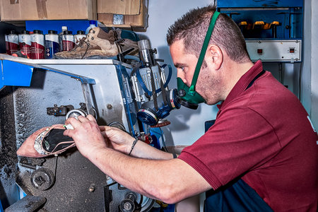 Young shoemaker mending footwear in repair shop.