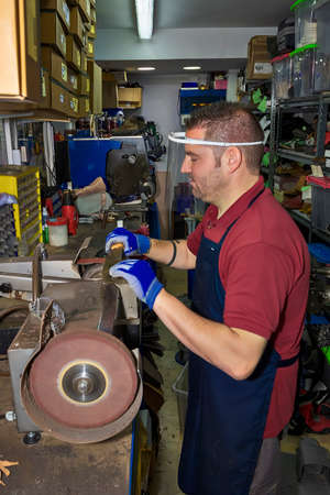 Young shoemaker mending footwear in repair shop.の写真素材