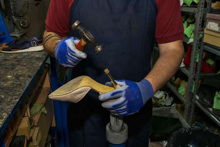 Young shoemaker mending footwear in repair shop.の写真素材