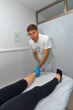 Physician working on examining a girls injured footの写真素材