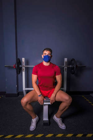 Break time. Young man in sportswear sitting in the gym.の写真素材