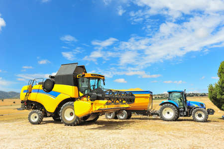 Photo of combine harvester that is harvesting wheat with dust straw in the air.の写真素材