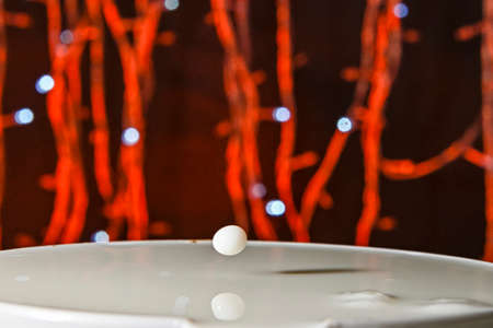 Drops falling on a container, with a bokeh background.の写真素材