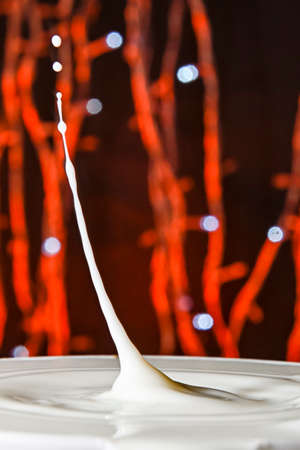 Drops falling on a container, with a bokeh background.の写真素材