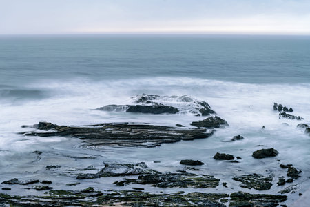 A serene view of Carriagem Beach in Portugal during sunset, with gentle waves lapping against the...