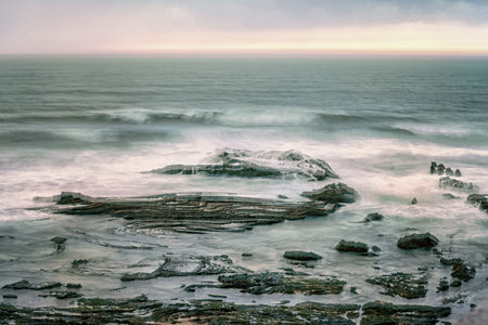 A serene view of Carriagem Beach in Portugal during sunset, with gentle waves lapping against the...