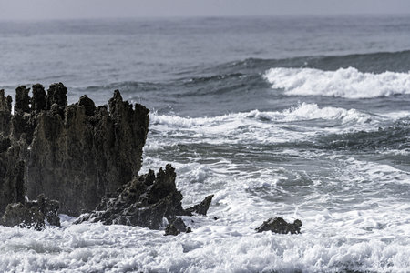 Powerful waves crashing against the rugged rocky shore at Amoreira Beach, Portugal. The dramatic...