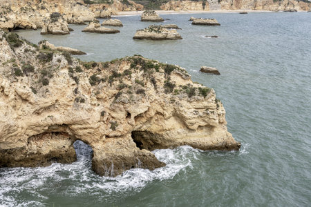 Stunning view of coastal rock formations and sea arches in Portimao, Portugal. The rugged cliffs and scattered sea stacks create a dramatic and picturesque seascape.の写真素材