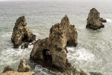 Stunning view of coastal rock formations and sea arches in Portimao, Portugal. The rugged cliffs and scattered sea stacks create a dramatic and picturesque seascape.の写真素材