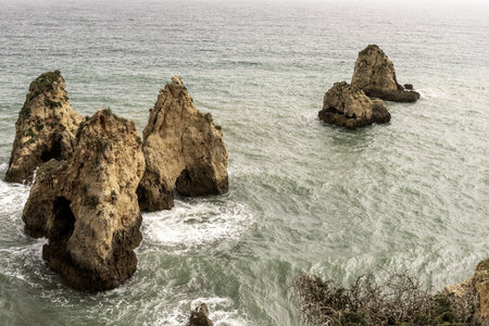 Stunning view of coastal rock formations and sea arches in Portimao, Portugal. The rugged cliffs and scattered sea stacks create a dramatic and picturesque seascape.の写真素材