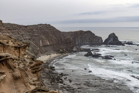 Scenic view of the rugged cliffs and the Atlantic Ocean at Cabo San Vicente, Portugal. The unique rock formations and misty atmosphere create a dramatic coastal landscape.の写真素材