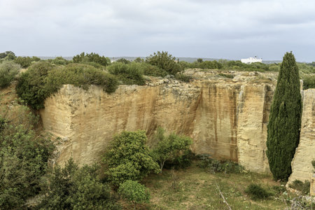 A captivating view of the ancient quarry walls at Lithica Pedreres de s'Hostal in Menorca, Spain, showcasing the impressive stone structures and natural greenery.の写真素材