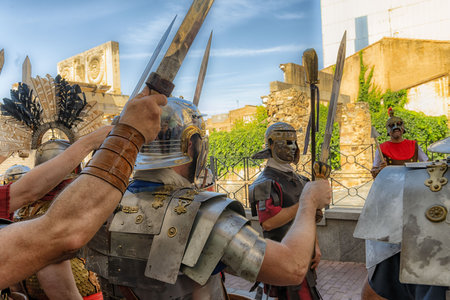 Enthusiastic reenactors dressed as Roman legionaries perform at the Roman Forum in Merida, Spain. The detailed costumes and historical setting bring ancient Roman military life to the present day.の写真素材