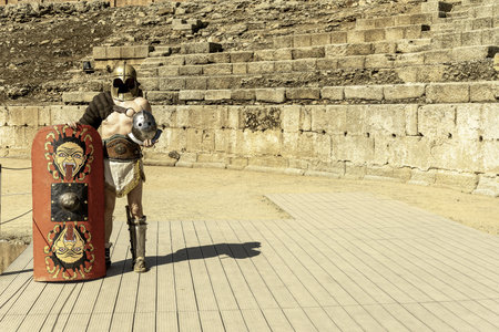 A reenactor dressed as a Roman gladiator poses with a shield and helmet in the ancient amphitheater of Merida, Spain.の写真素材