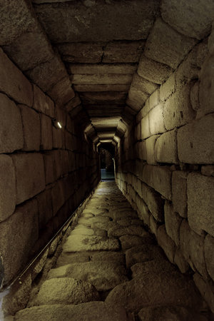 A dimly lit stone passageway leading to an ancient structure in Merida, Spain. The rugged steps and walls showcase the architectural ingenuity of historical timesの写真素材