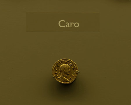 Ancient gold coin featuring the profile of Carus, Roman Emperor. Displayed in a museum exhibit,...
