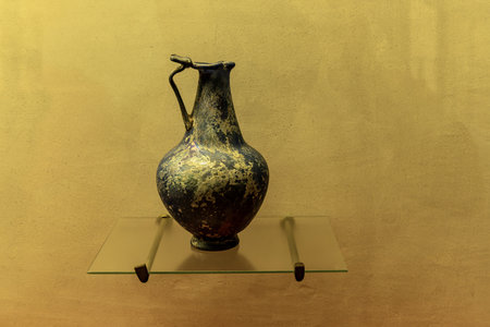 An ancient Roman green glass vase with intricate design. Features a wide body, a narrow neck, and decorative handles, showcasing Roman glassmaking craftsmanship.の写真素材