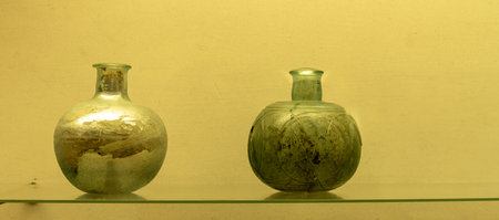 An ancient Roman green glass vase with intricate design. Features a wide body, a narrow neck, and decorative handles, showcasing Roman glassmaking craftsmanship.の写真素材