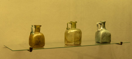 An ancient Roman green glass vase with intricate design. Features a wide body, a narrow neck, and...