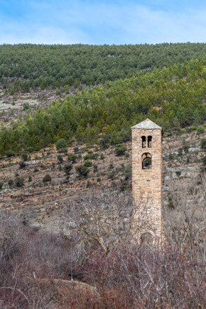 Old stone bell tower of San Miguel in Yanguas, Soria, standing tall against a green mountainous background.の写真素材