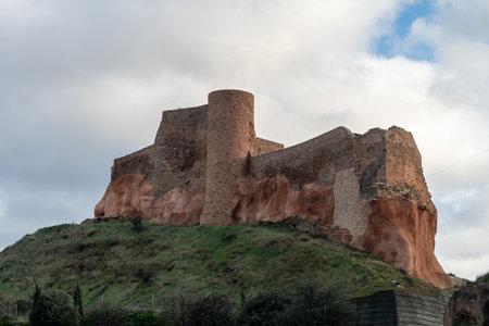 The historic ruins of the Castle of Arnedo, La Rioja, Spain, built on a rocky hill with stone walls and a cylindrical tower, under a cloudy sky.の写真素材