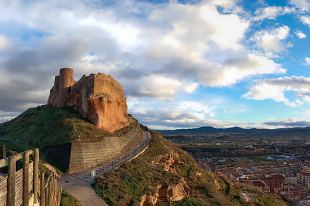 The historic ruins of the Castle of Arnedo, La Rioja, Spain, built on a rocky hill with stone walls and a cylindrical tower, under a cloudy sky.の写真素材