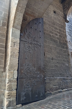 Ornate wrought iron medieval door with floral patterns, set in an ancient stone archway in Laguardia, Spain.の写真素材
