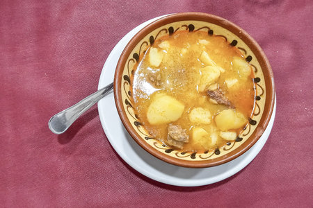 A bowl of patatas a la riojana, a traditional Spanish stew made with potatoes, chorizo, and paprika, served on rustic tableware.の写真素材