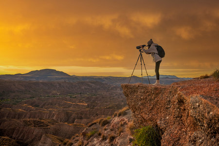 Girl observing the badland landscape, at sunset in the desert of the Granada Geopark.