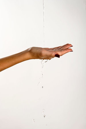 hands of a young woman dripping clear water, white background
